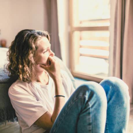 Woman sitting by a window, head resting in her hand — anxiety support with Natalie Hall.