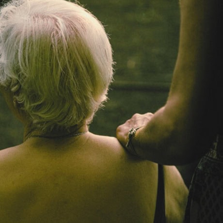 Woman sitting facing away, with supportive hand on her shoulder — stress support with Natalie Hall.